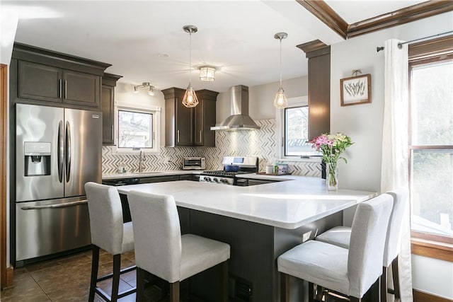 kitchen with backsplash, wall chimney exhaust hood, appliances with stainless steel finishes, and a sink