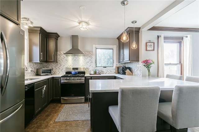 kitchen with a peninsula, a breakfast bar area, appliances with stainless steel finishes, wall chimney exhaust hood, and decorative backsplash