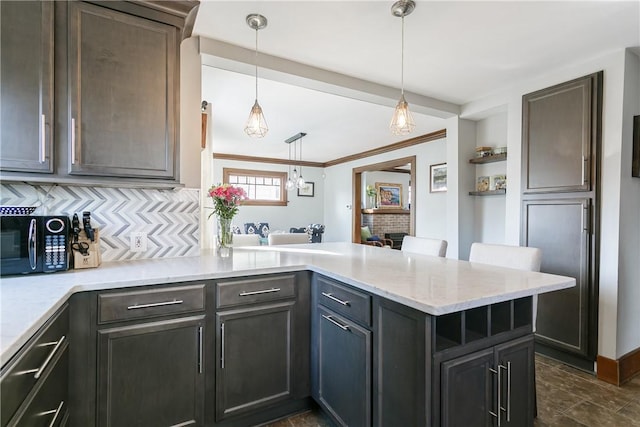 kitchen featuring ornamental molding, tasteful backsplash, a peninsula, black microwave, and hanging light fixtures