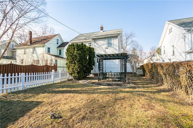 back of house featuring a chimney, fence private yard, a pergola, and a lawn