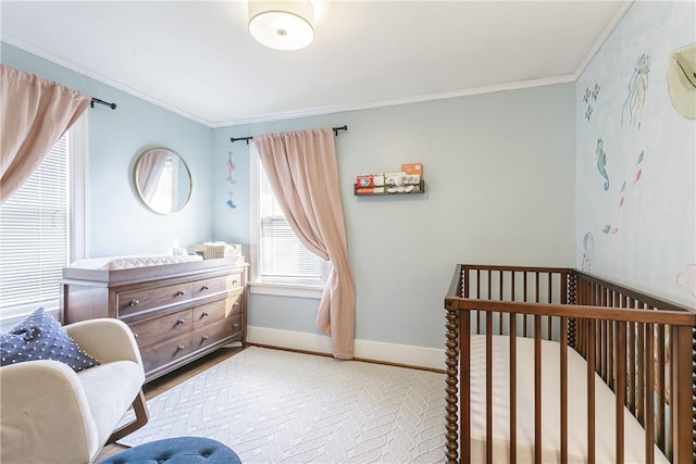 bedroom featuring crown molding, a nursery area, and baseboards