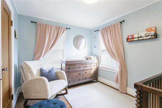 bedroom featuring a crib, wood finished floors, baseboards, and ornamental molding