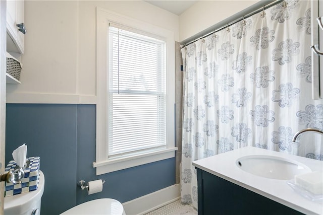 bathroom with toilet, vanity, and baseboards