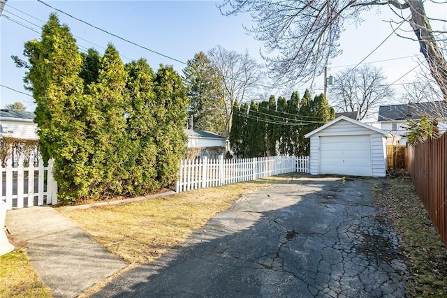 view of yard with an outbuilding, fence private yard, a garage, and driveway