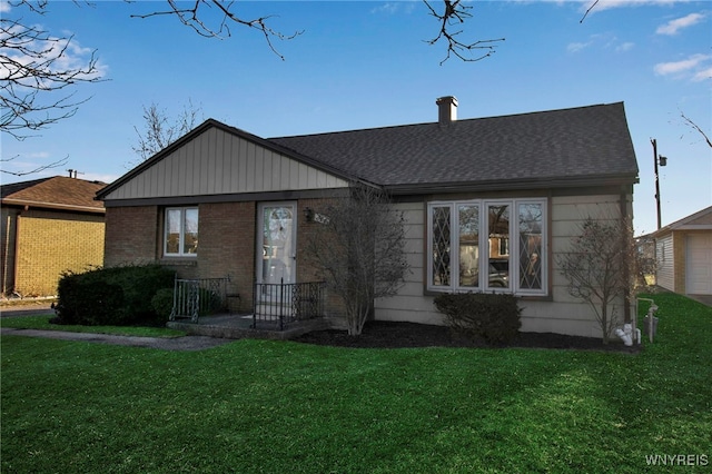 view of front of property with brick siding, a front lawn, and a shingled roof