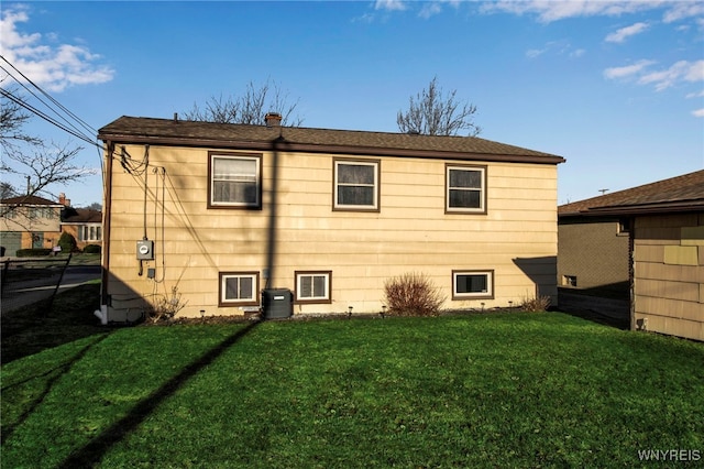 rear view of property with a lawn and central AC