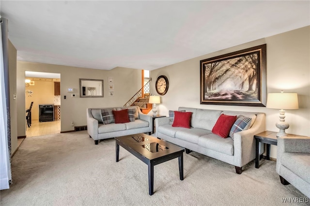 living area with baseboards, light carpet, beverage cooler, and stairs