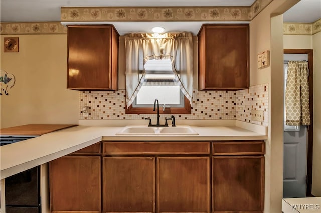 kitchen with tasteful backsplash, brown cabinets, light countertops, and a sink