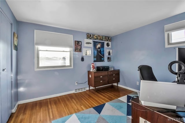 office area with visible vents, baseboards, and wood finished floors