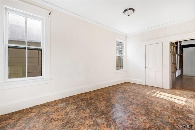 empty room featuring stone finish flooring and baseboards