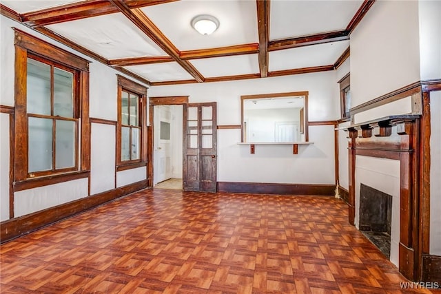 unfurnished living room featuring baseboards, coffered ceiling, a fireplace, crown molding, and beamed ceiling