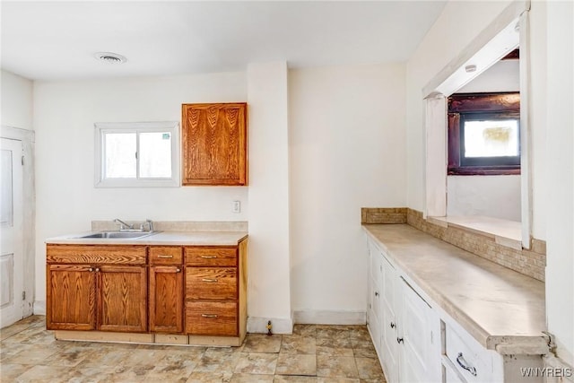 kitchen with a sink, visible vents, brown cabinets, and a healthy amount of sunlight