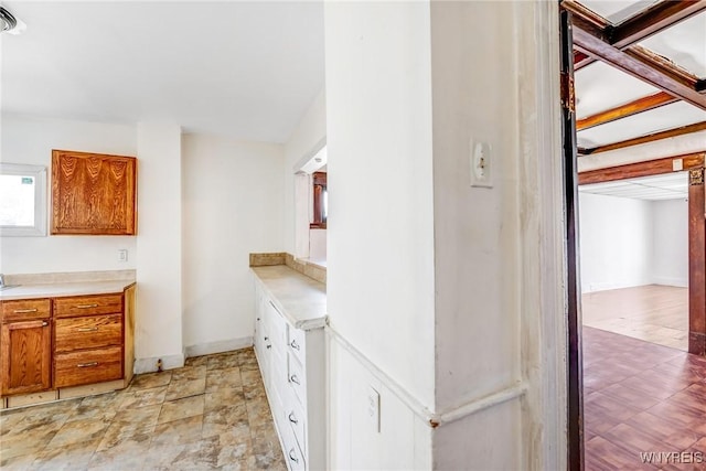 kitchen featuring light countertops, brown cabinetry, and baseboards