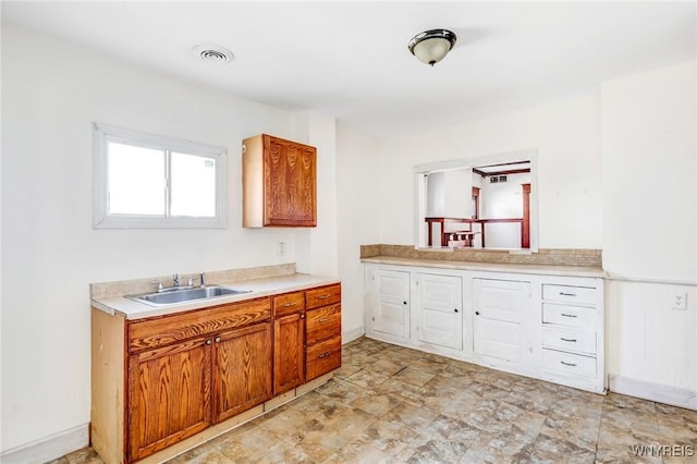 kitchen with a sink, visible vents, brown cabinets, and light countertops