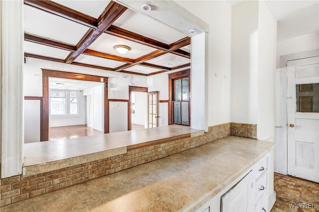 kitchen featuring coffered ceiling, beam ceiling, decorative backsplash, light countertops, and white cabinetry