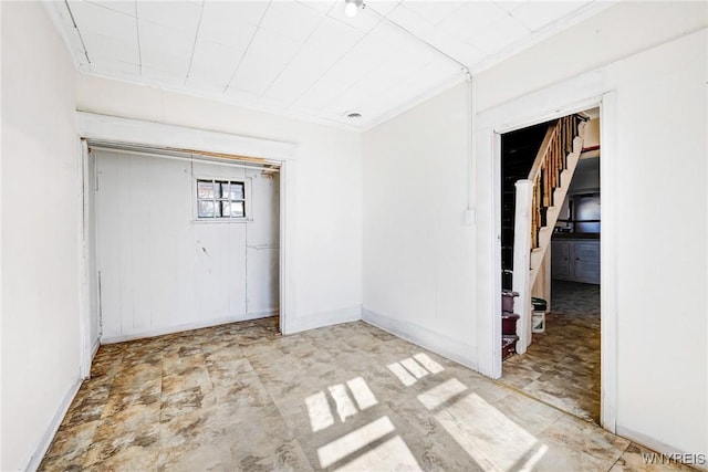 unfurnished room with stairs, baseboards, and ornamental molding