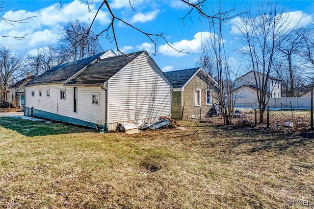 view of side of home with a yard and fence