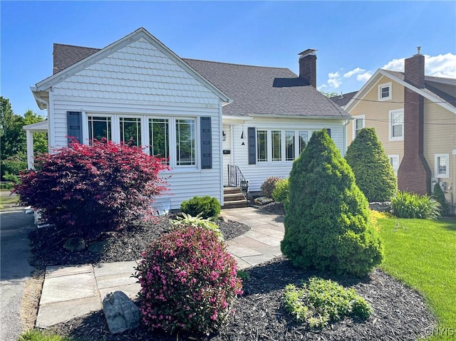 view of front facade featuring a front lawn and roof with shingles