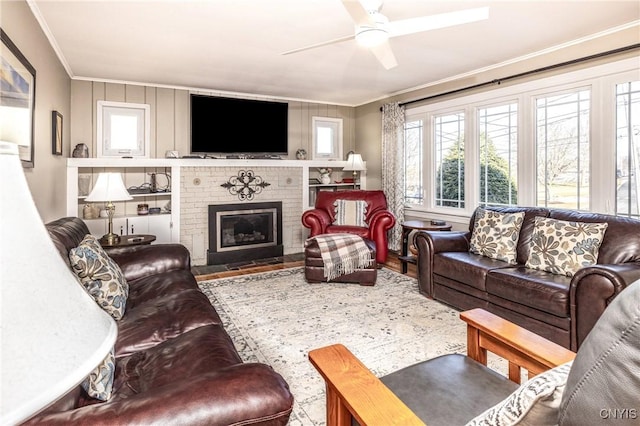 living room with crown molding, a brick fireplace, and a ceiling fan