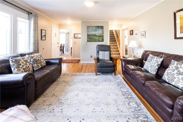 living room featuring stairs, crown molding, baseboards, and wood finished floors