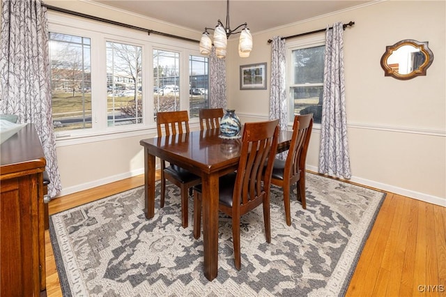 dining room with a wealth of natural light, baseboards, wood finished floors, and crown molding