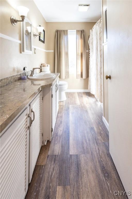 full bathroom featuring visible vents, toilet, wood finished floors, baseboards, and vanity