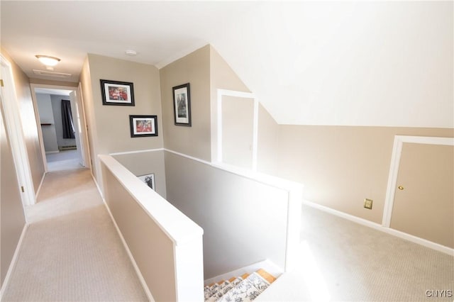 corridor with an upstairs landing, light colored carpet, and baseboards