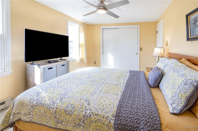 bedroom with a closet, baseboard heating, and a ceiling fan