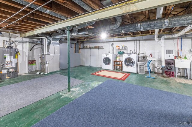 unfinished basement featuring washer and clothes dryer, heating unit, gas water heater, and a sink