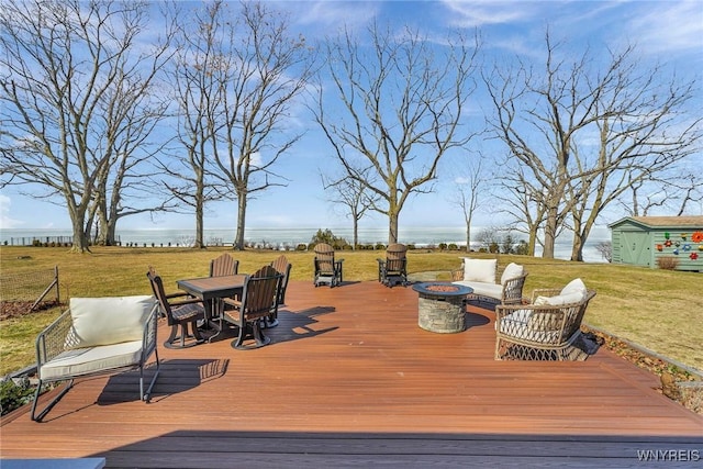 wooden deck featuring an outdoor fire pit and a yard