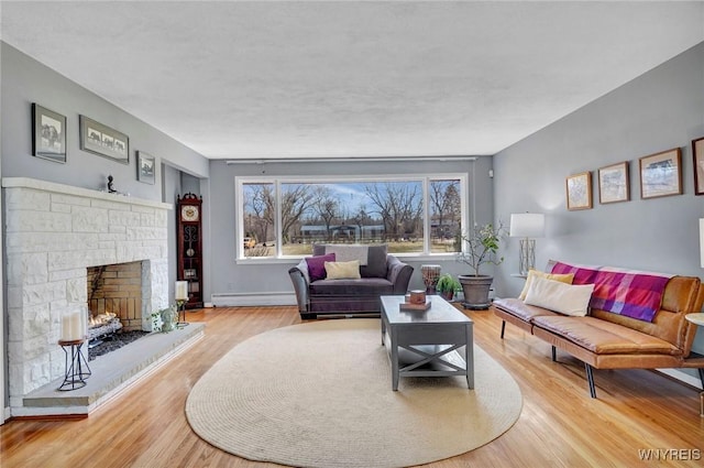 living area featuring a stone fireplace, wood finished floors, baseboards, and baseboard heating