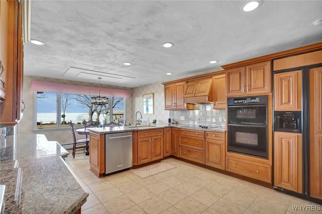 kitchen featuring brown cabinets, black appliances, a sink, light stone counters, and a peninsula