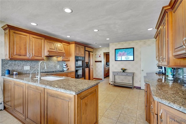 kitchen with a sink, light stone countertops, brown cabinets, and dobule oven black