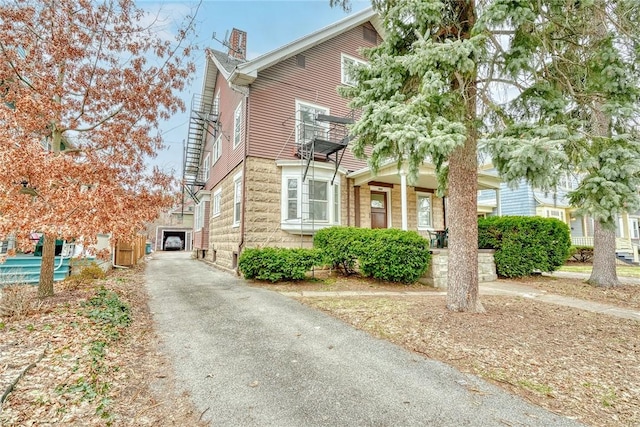 view of side of property featuring an outdoor structure, a balcony, and a chimney