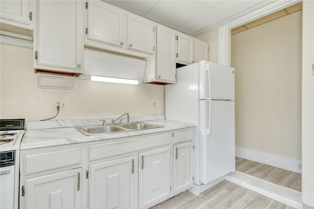 kitchen with white cabinetry, light countertops, freestanding refrigerator, and a sink