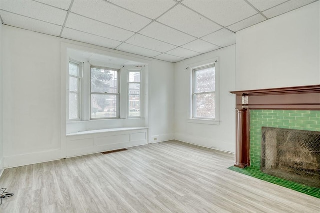 unfurnished living room featuring visible vents, baseboards, a fireplace with flush hearth, wood finished floors, and a paneled ceiling