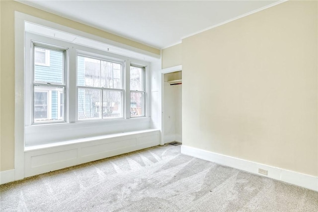 spare room with crown molding, light colored carpet, and baseboards