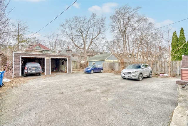 view of parking with a garage and fence