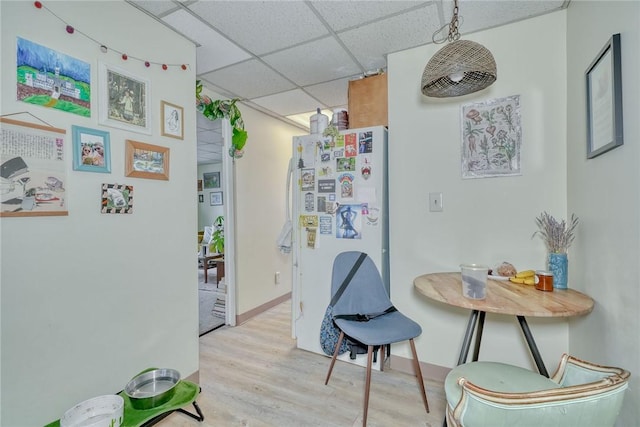 interior space featuring a drop ceiling, baseboards, and wood finished floors