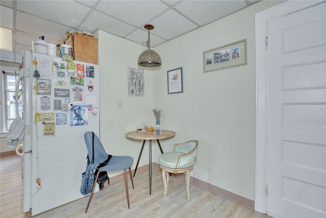 dining room with a drop ceiling, baseboards, and wood finished floors