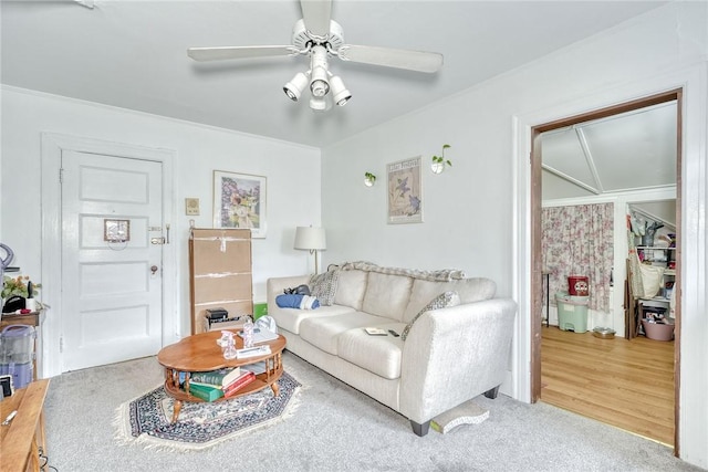 carpeted living area with crown molding and a ceiling fan