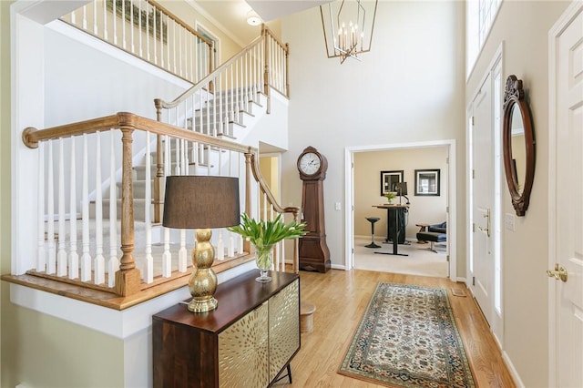 entrance foyer featuring stairway, a high ceiling, wood finished floors, and a chandelier