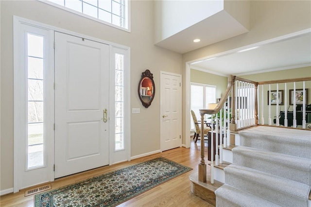 foyer entrance featuring stairway, wood finished floors, visible vents, and a healthy amount of sunlight