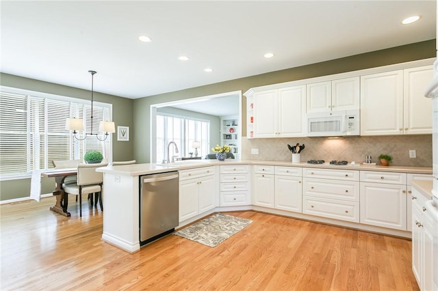 kitchen with white cabinetry, white appliances, a peninsula, and light wood-style floors