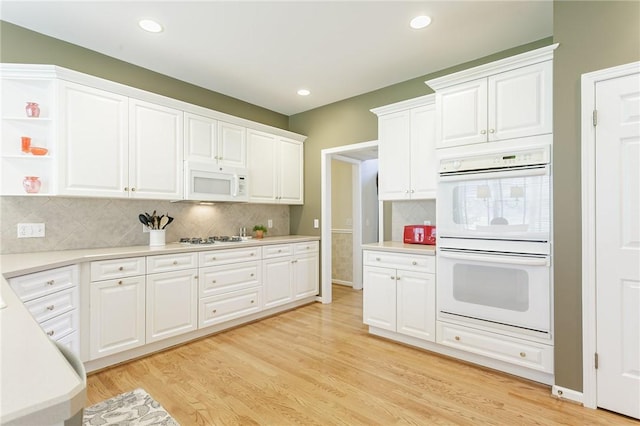 kitchen with light wood finished floors, light countertops, decorative backsplash, white cabinets, and white appliances