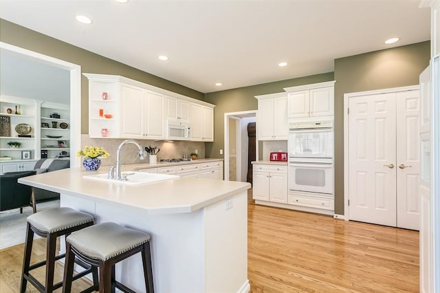 kitchen with a sink, open shelves, white cabinetry, white appliances, and a peninsula