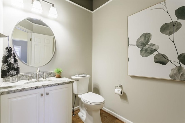 bathroom with baseboards, toilet, wood finished floors, and vanity