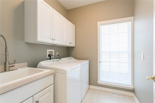 clothes washing area featuring washer and dryer, cabinet space, visible vents, and baseboards