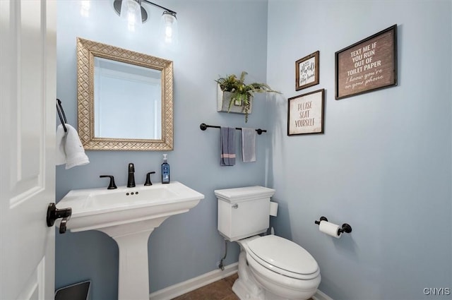 bathroom with a sink, baseboards, toilet, and tile patterned floors