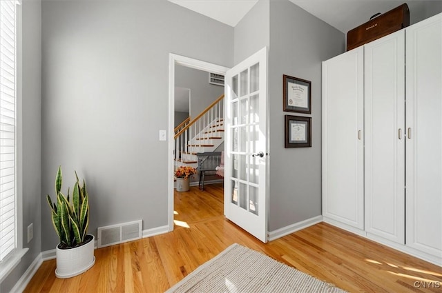 entrance foyer with stairway, light wood-style floors, visible vents, and baseboards